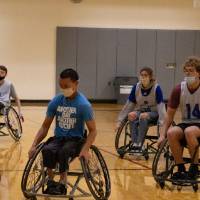 Adults chasing a basketball during a wheelchair basketball game.